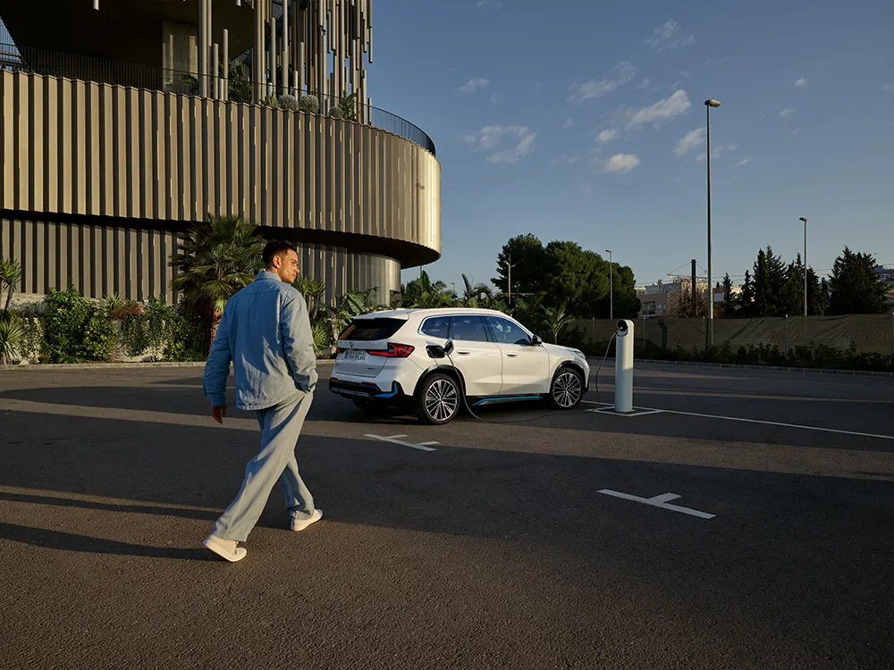 Person standing next to a bright blue BMW car
