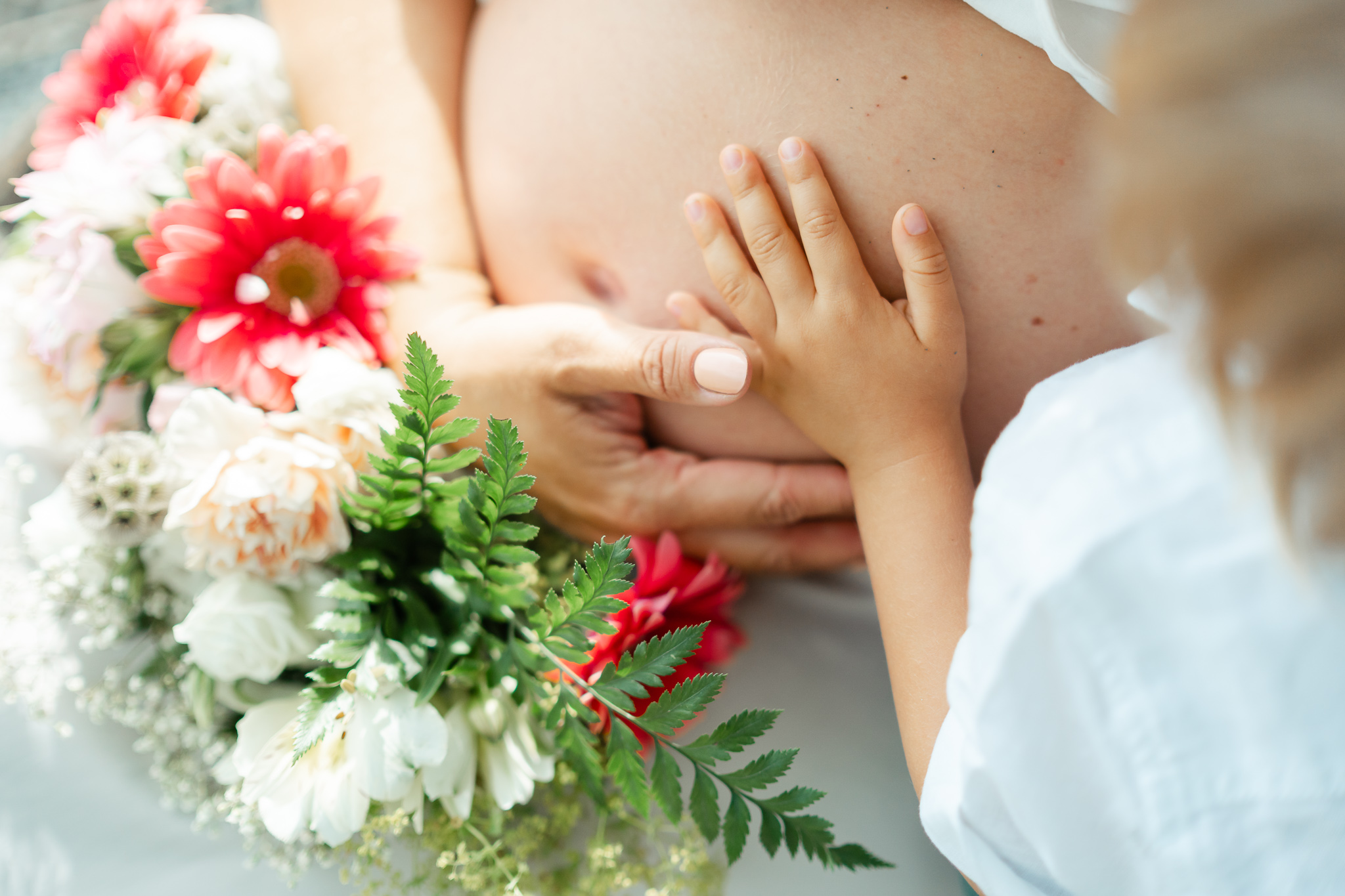 Kinderhand und Mamas Hand auf Babybauch 