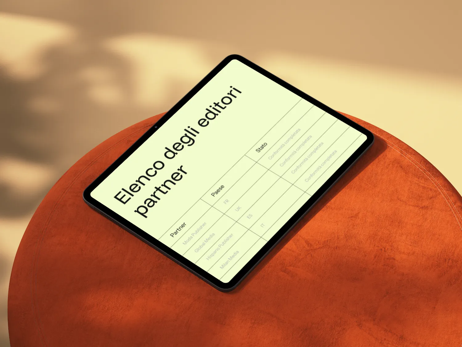 Tablet on an orange surface displaying a list titled 'Elenco degli editori partner' with a table of partner names, countries, and statuses in Italian.