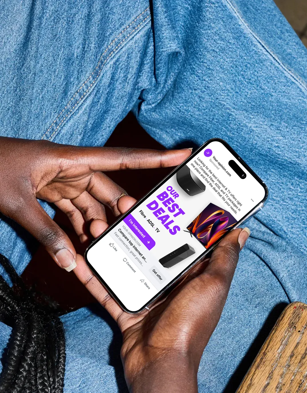 Person holding a smartphone displaying an internet and TV service ad with text 'OUR BEST DEALS' and images of a TV and router.