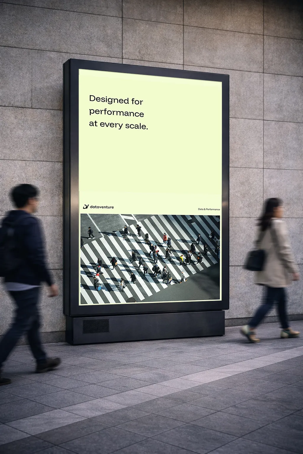 Outdoor digital billboard on a tiled wall showing an advertisement with text 'Designed for performance at every scale' above an aerial photo of people crossing a striped pedestrian crosswalk.