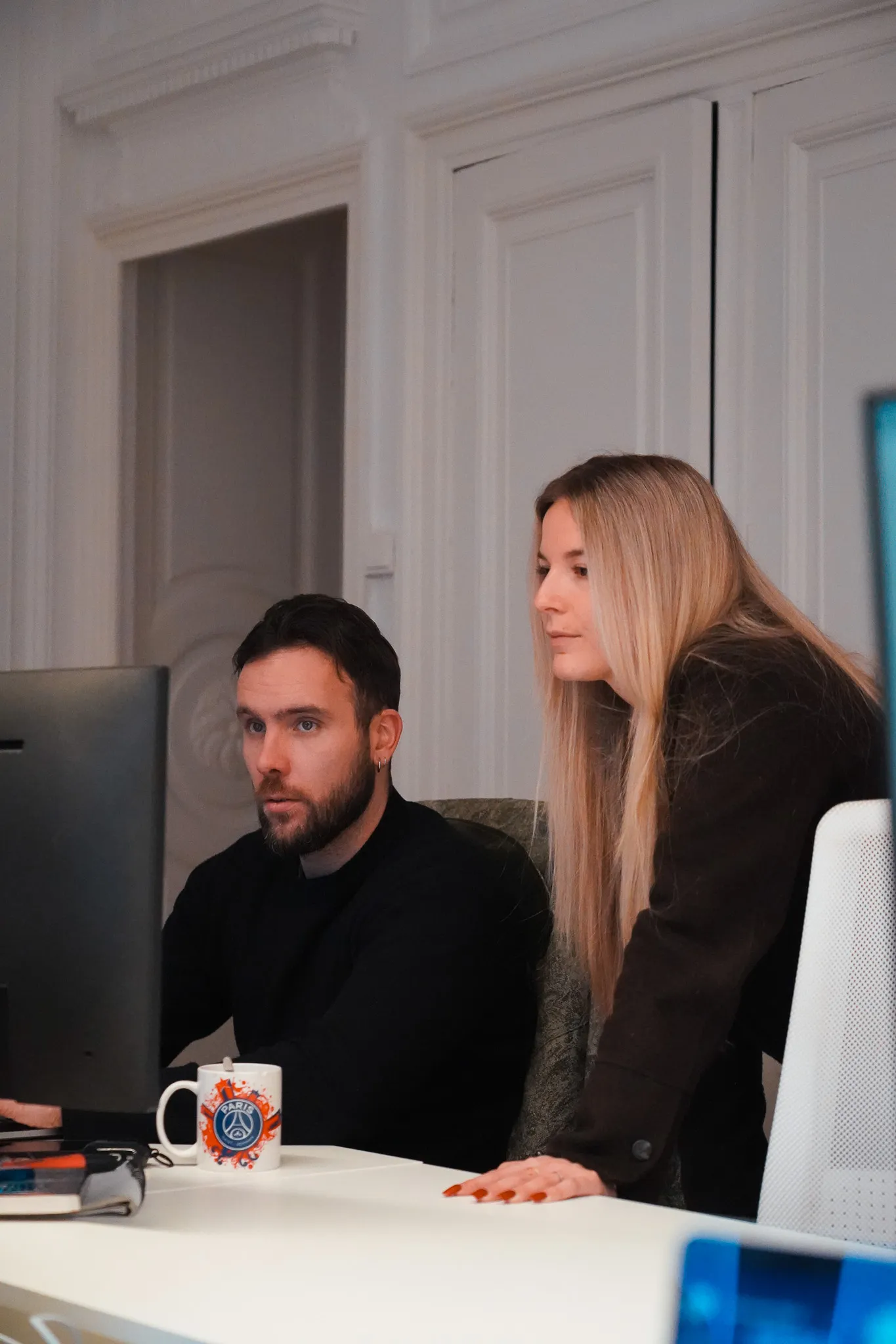 Man and woman working together attentively at a computer in an office setting.
