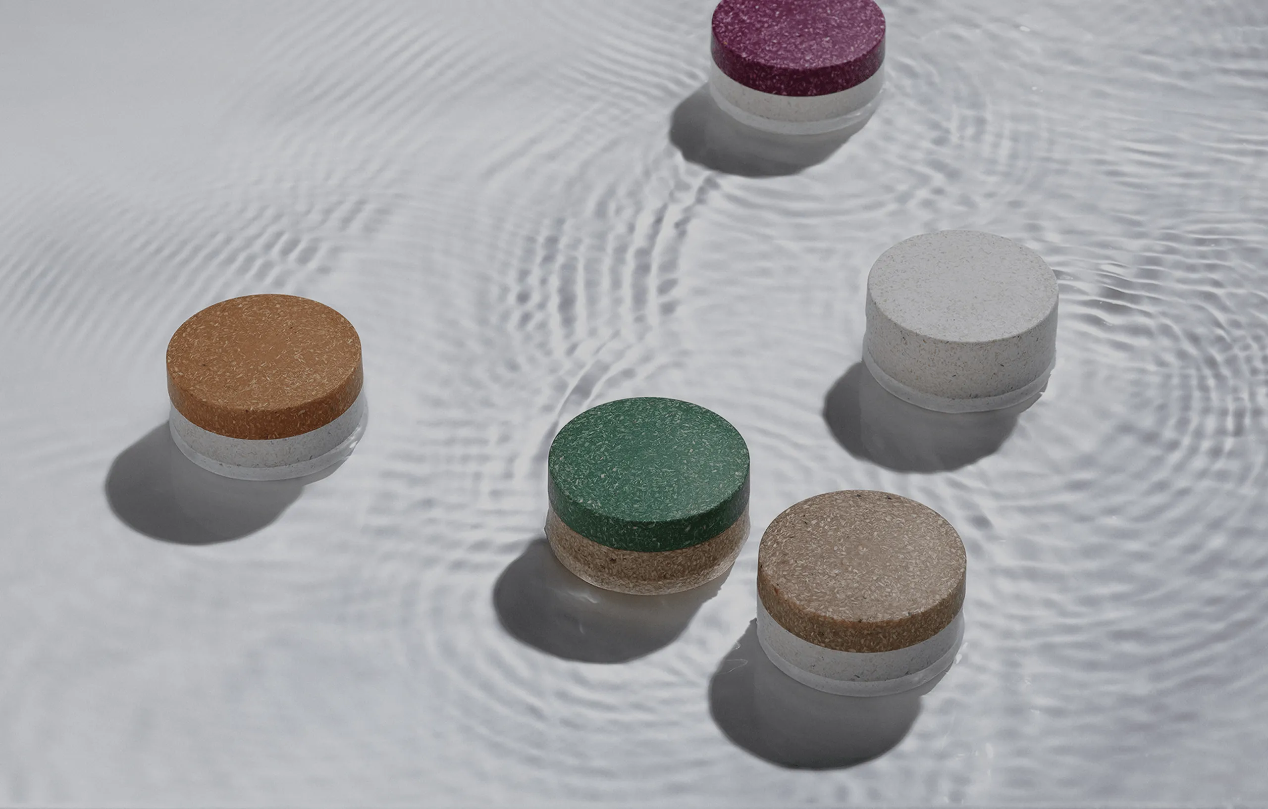 Colorful eco-friendly round containers floating on water.