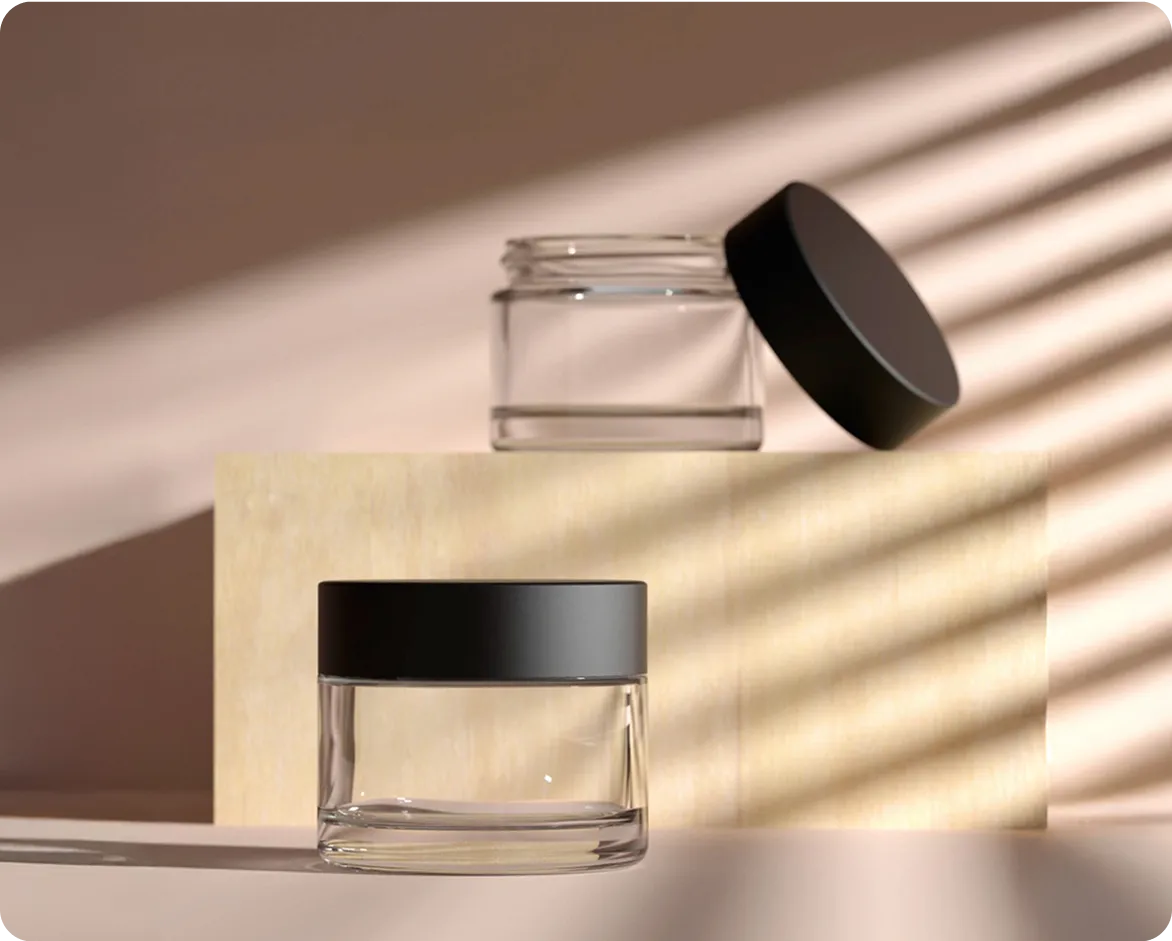 Clear glass cosmetic jars with black lids in natural light and shadow.