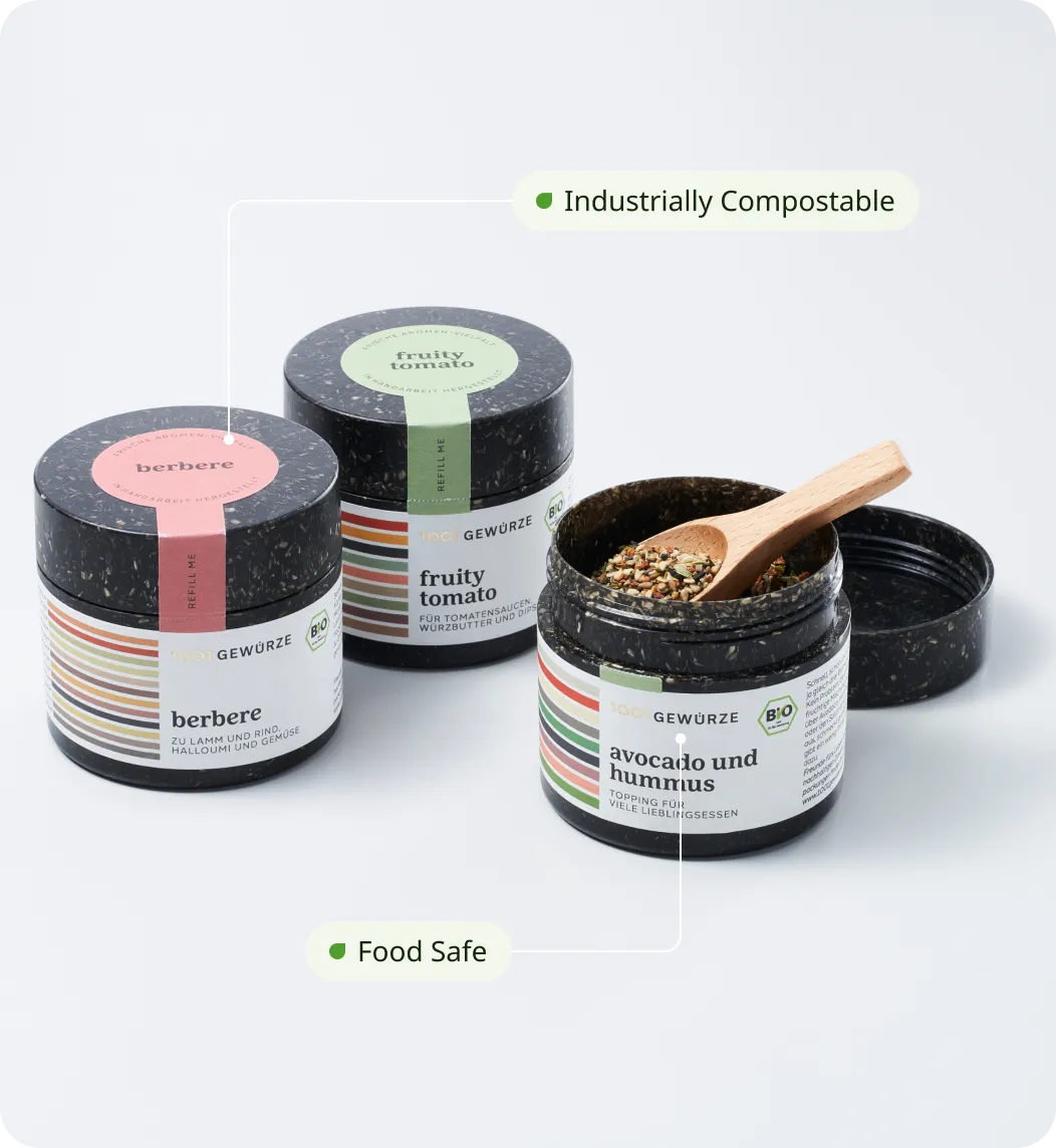 This image shows three eco-friendly spice containers labeled “berbere,” “fruity tomato,” and “avocado und hummus.” The jars are made from a microplastic-free and food-safe material, emphasizing sustainable and safe packaging for food products.