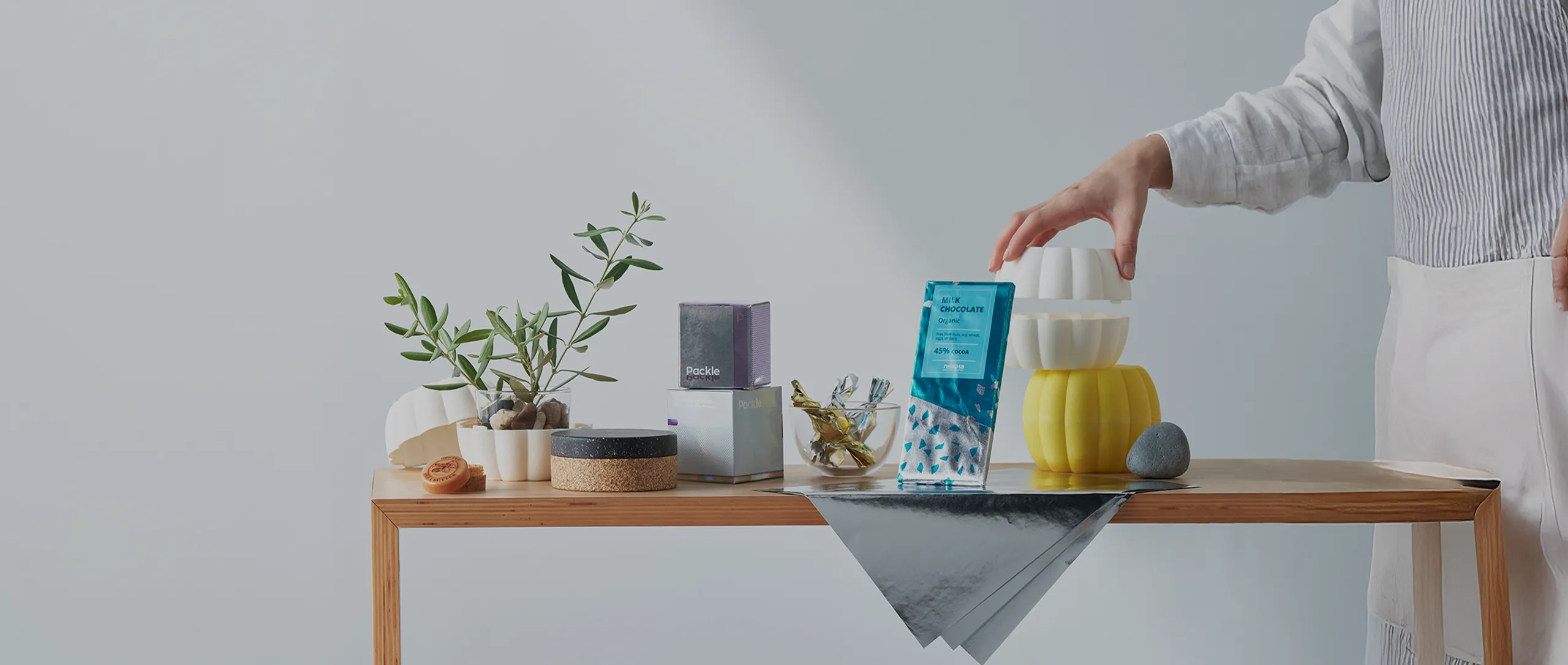 Eco-friendly product and packaging samples arranged on a wooden table, representing Nissha’s commitment to sustainable design and innovation.