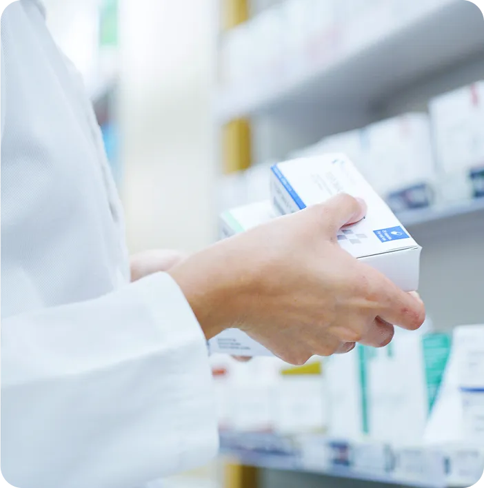 Pharmacist holding medicine boxes in a pharmacy, representing healthcare quality, medical packaging, and professional pharmaceutical services.