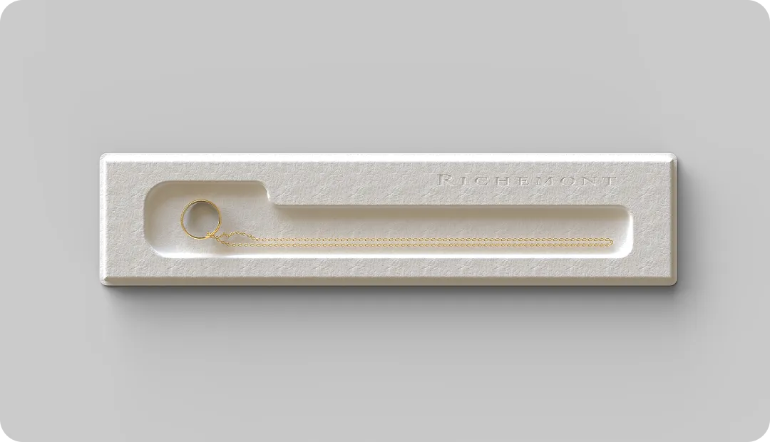 Luxury molded fiber jewelry tray with gold ring and chain, featuring sustainable packaging design embossed with Richemont branding.