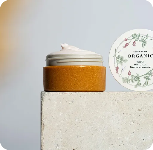 Organic face cream jar with natural amber base and botanical lid design labeled Nissha ecosense, showcasing sustainable skincare packaging.