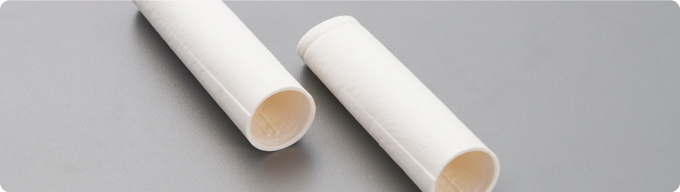 Eco-friendly molded fiber tubes on gray surface, showcasing sustainable paper-based packaging components for medical or cosmetic applications.