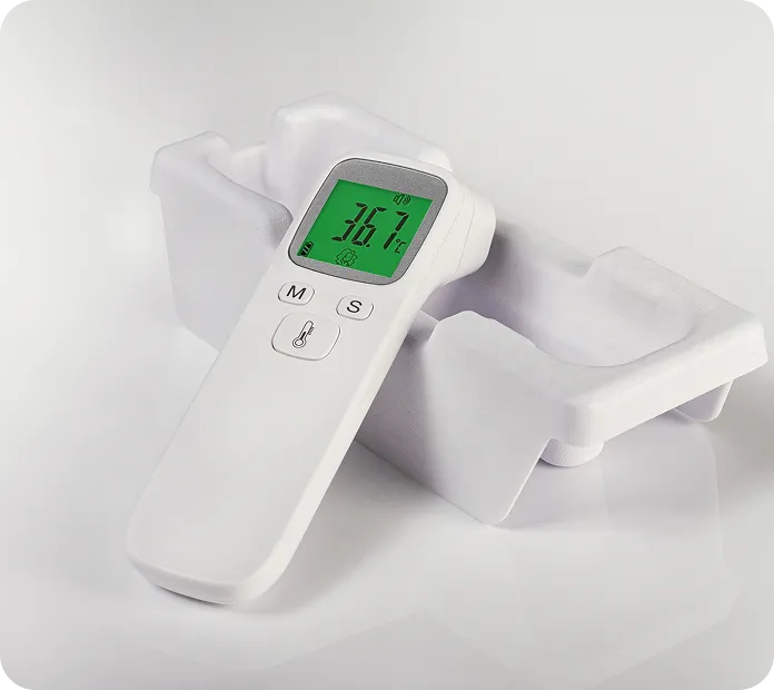 Digital infrared thermometer with green LCD display on eco-friendly molded pulp tray, showcasing sustainable medical device packaging.