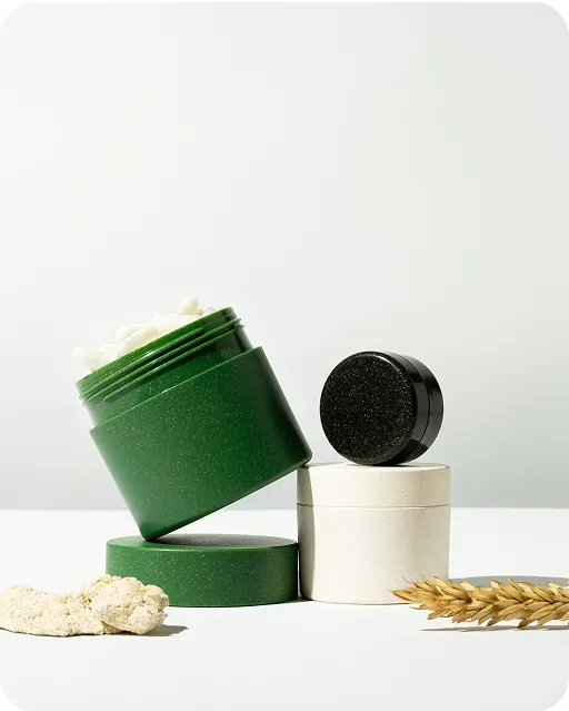 Eco-friendly cosmetic jars in green, white, and black with natural elements on a light background, showcasing sustainable skincare packaging design.