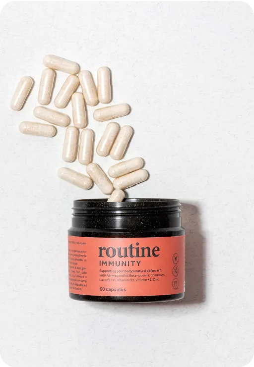 Routine Immunity supplement jar with orange label and white capsules spilling out on a light surface, representing sustainable wellness packaging.
