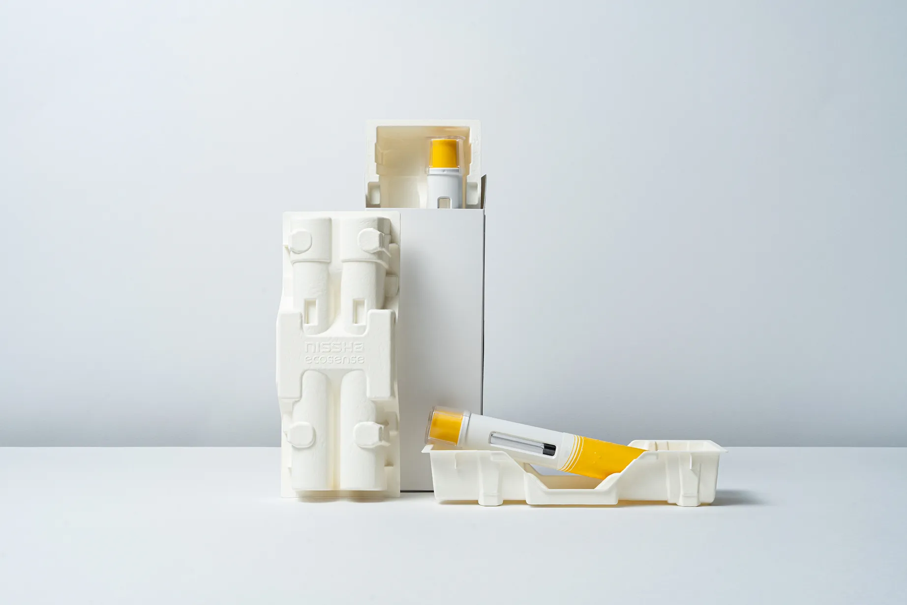 Eco-friendly molded fiber medical packaging holding two yellow injector pens, designed for sustainable and secure pharmaceutical storage.