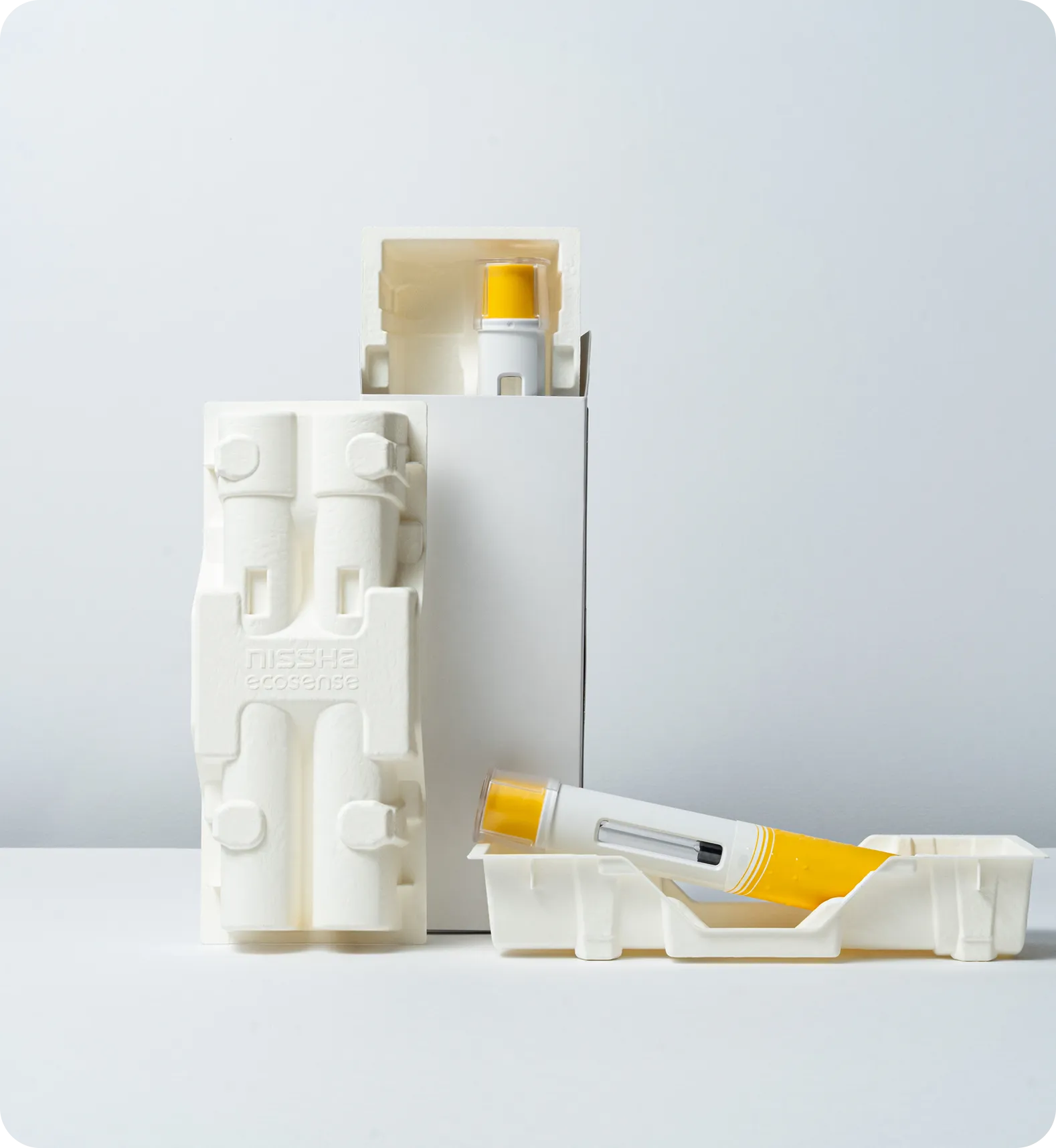 Eco-friendly molded fiber medical packaging holding two yellow injector pens, designed for sustainable and secure pharmaceutical storage.