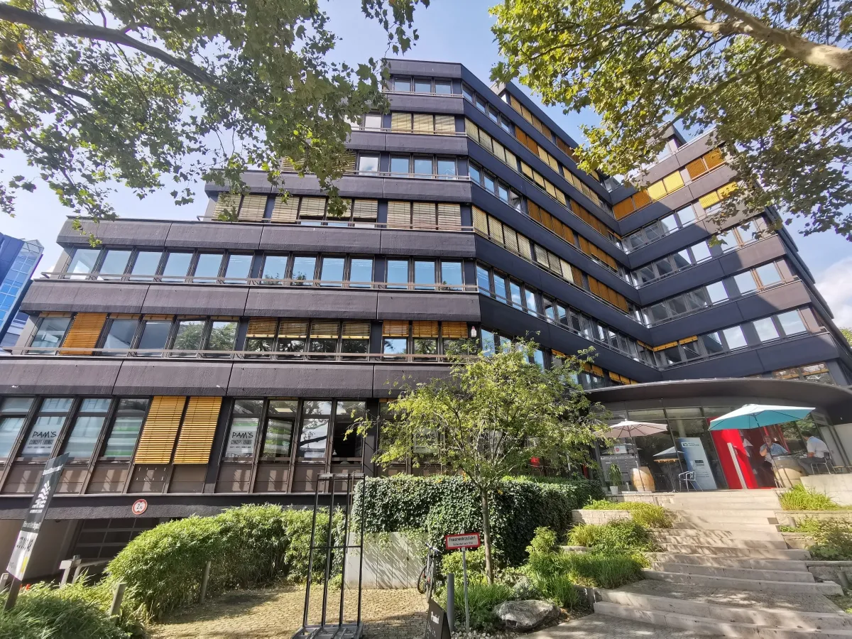 Nissha headquarters building surrounded by trees and parking area under a clear blue sky, representing the company’s commitment to innovation and sustainability.