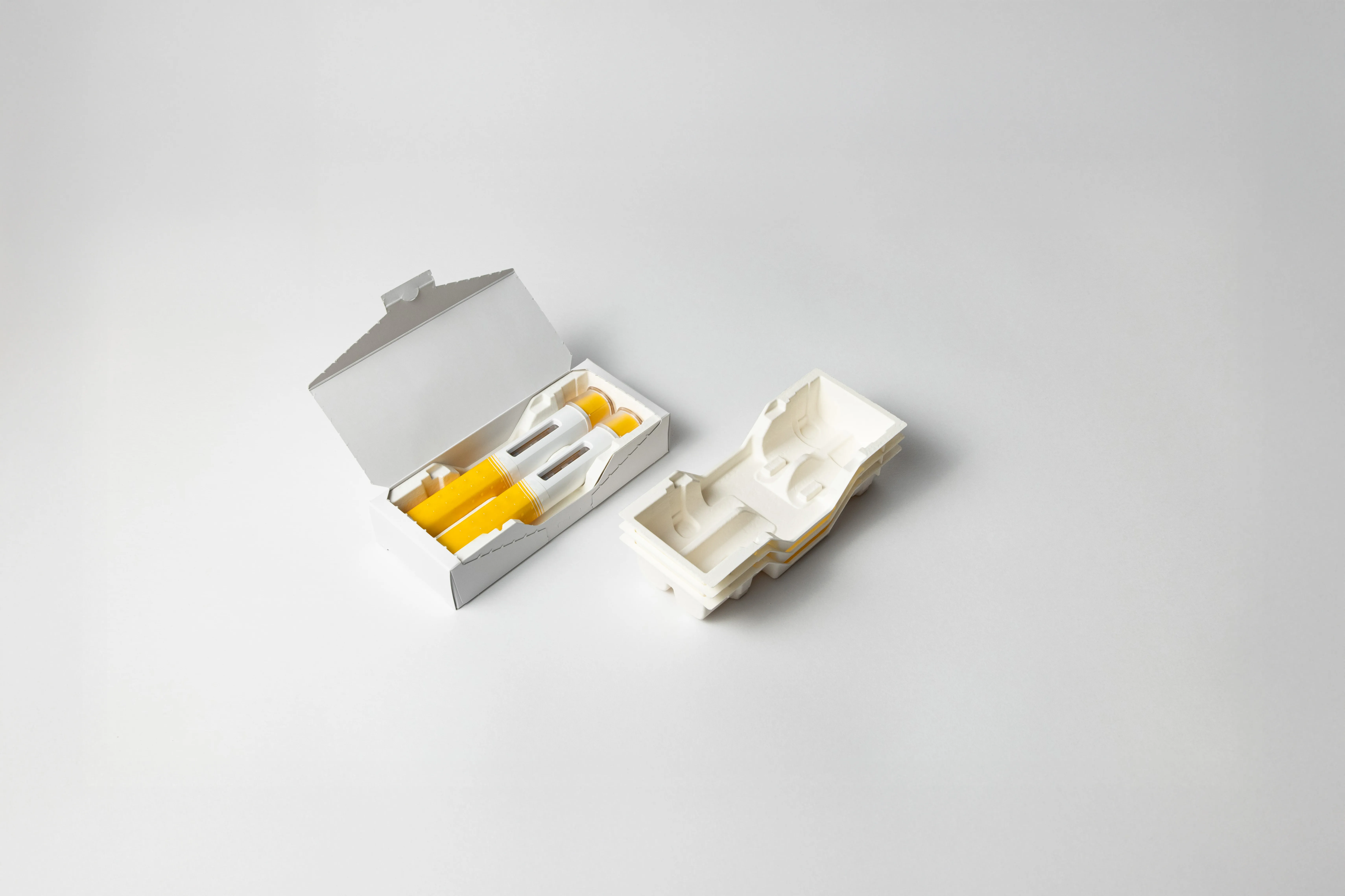 Sustainable molded fiber packaging with eco-friendly inserts holding yellow vials, showcasing protective and recyclable design for medical or cosmetic products.