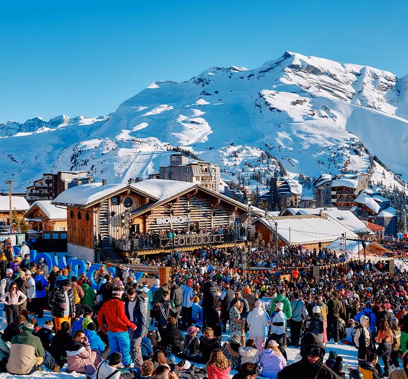 Big crowds gather to enjoy music at Folie Douce, snowy mountains in the background