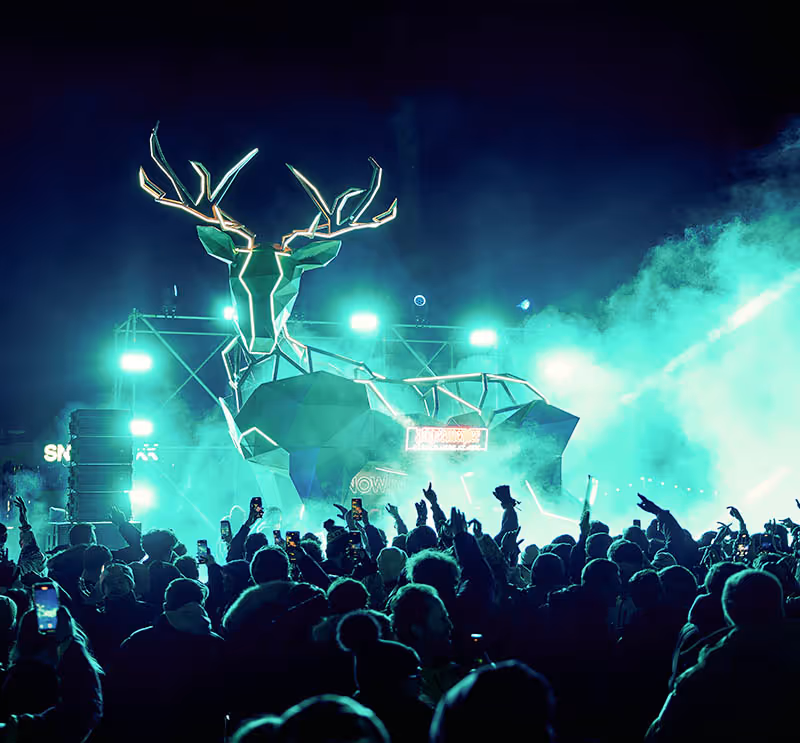 Stag stage at Snowboxx, crowd gathers in front of Jagermeister branded stag construction surrounded by smoke and teal coloured lighting at night