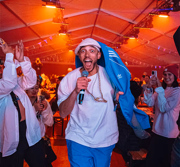 Man performing karaoke in front of crowd at an indoor stage