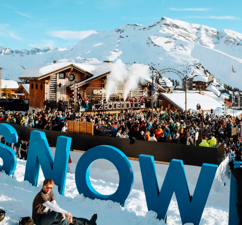 Big crowds gather to enjoy music at Folie Douce, snowy mountains in the background