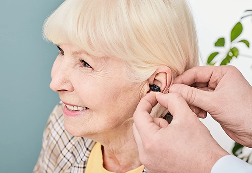 Einsetzen eines modernen Hörgeräts durch einen erfahren Hörexperten