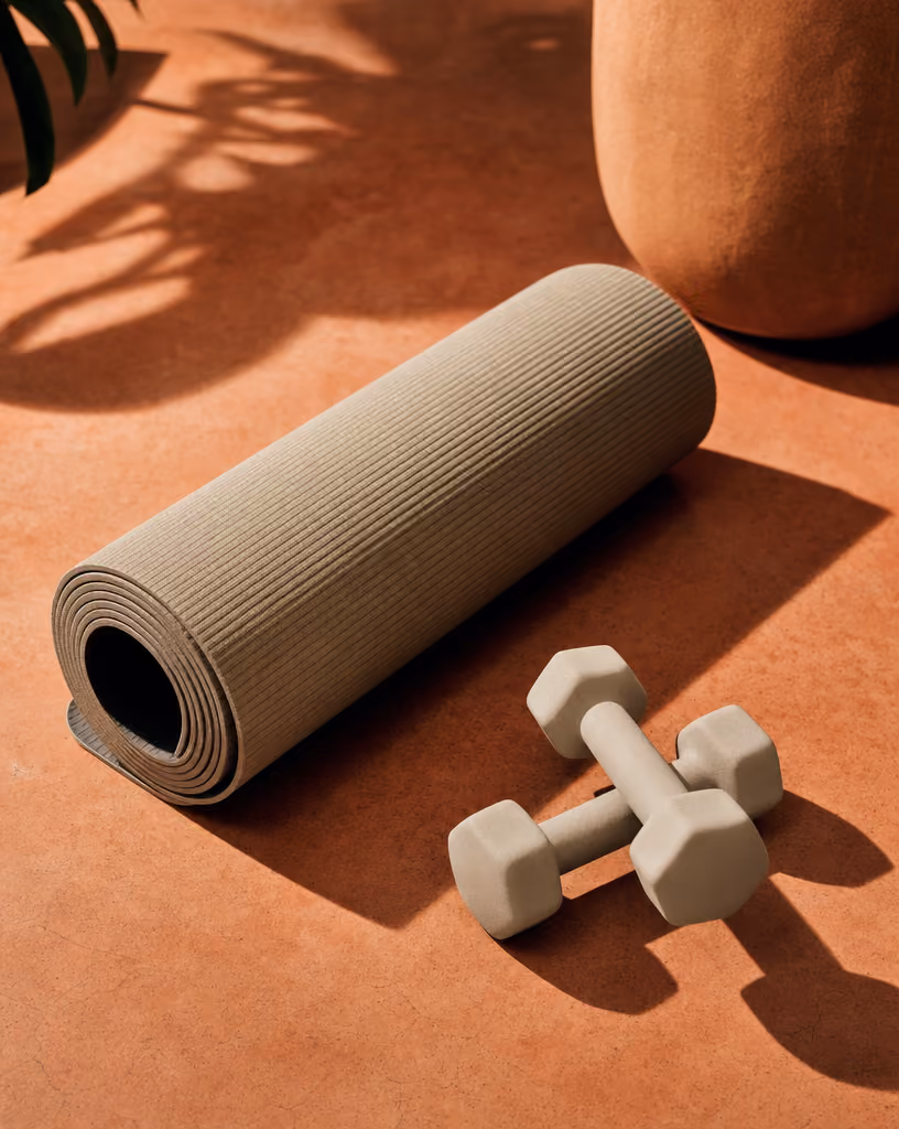 Opgerolde yogamat met halters, klaar voor krachttraining thuis