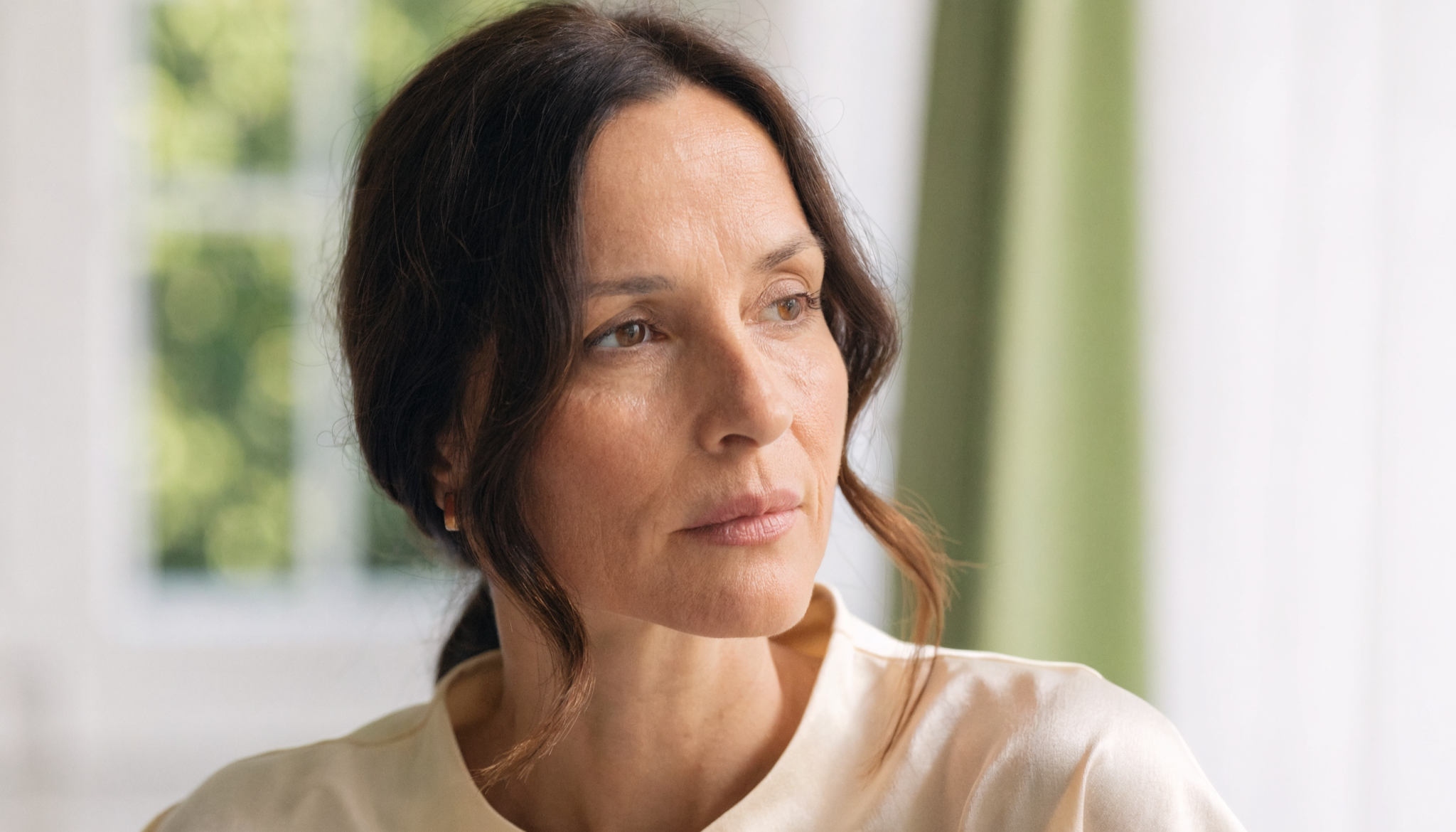 Vrouw van begin veertig kijkt rustig uit het raam