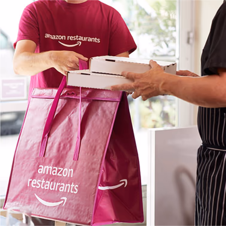 Delivery person handing food container to customer at doorway.