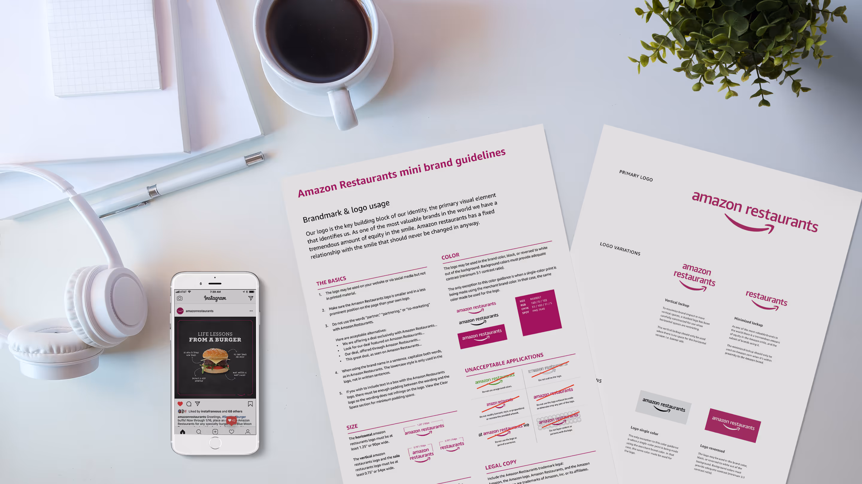 Desktop workspace with Amazon Restaurants brand guidelines documents, coffee cup, and phone displaying burger infographic on Instagram.