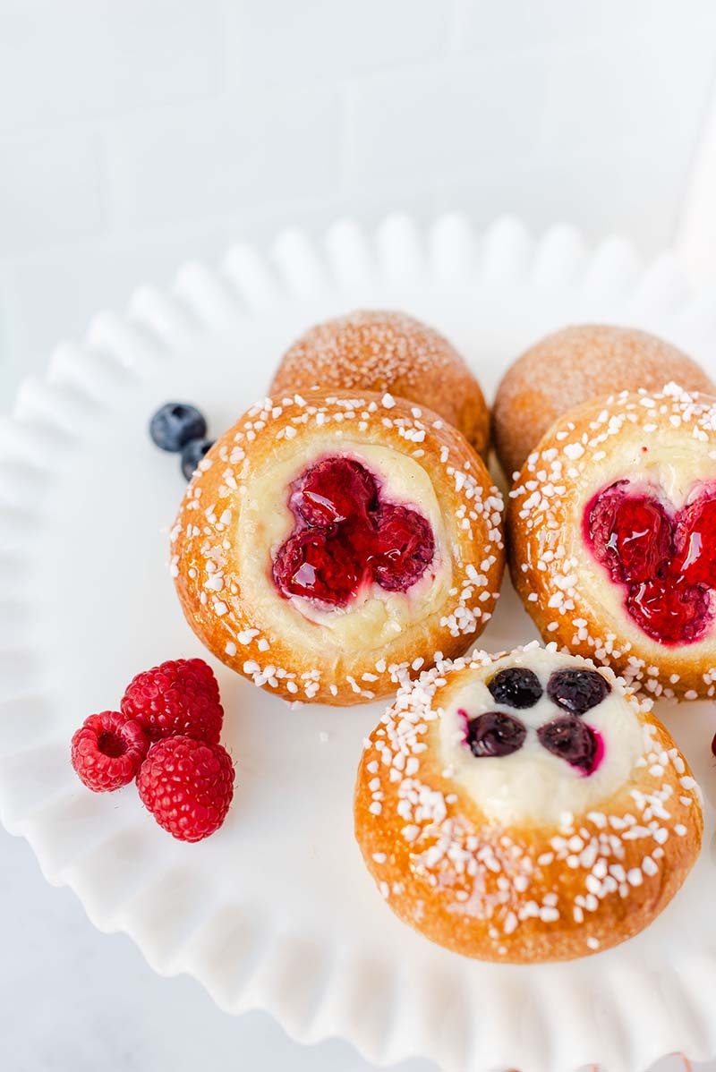 A plate of pastries with berries and powdered sugar.