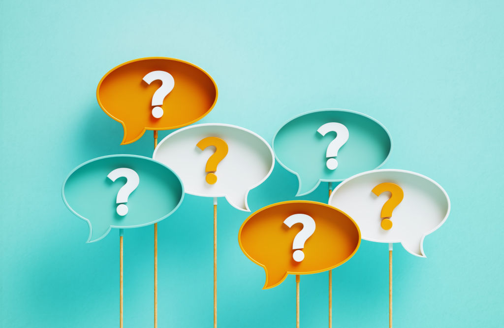 Six colorful speech bubbles in shades of teal, orange, and white, each containing a large question mark, symbolizing discussion, curiosity, and seeking answers.