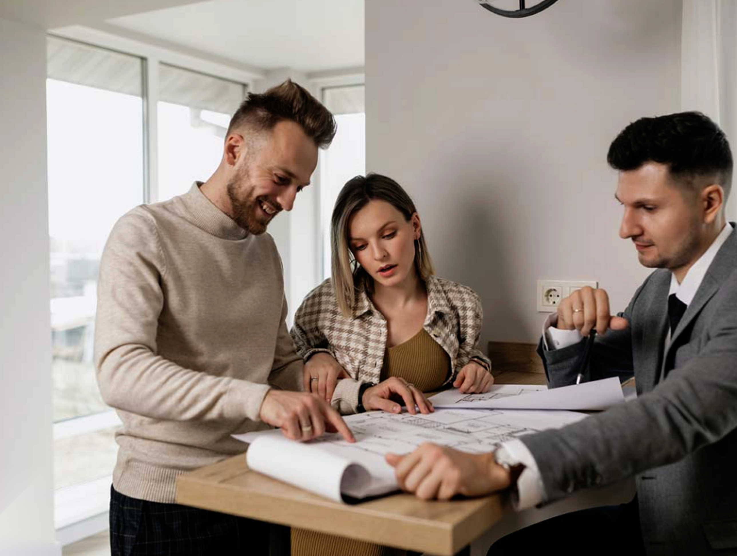 A couple signing real estate documents with a professional agent in a modern, well-lit apartment.