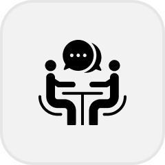 Icon showing two people sitting at a table having a conversation with speech bubbles above them.