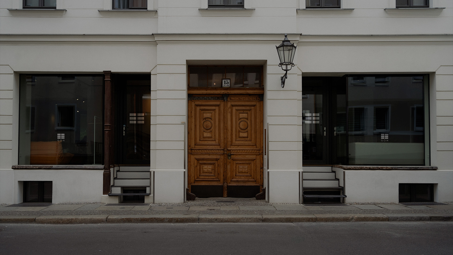 Tattoo-Künstler skizziert ein klassisches Gesichtsbild auf dem Unterarm einer Person, mit einer digitalen Referenz auf einem Tablet nebenan.