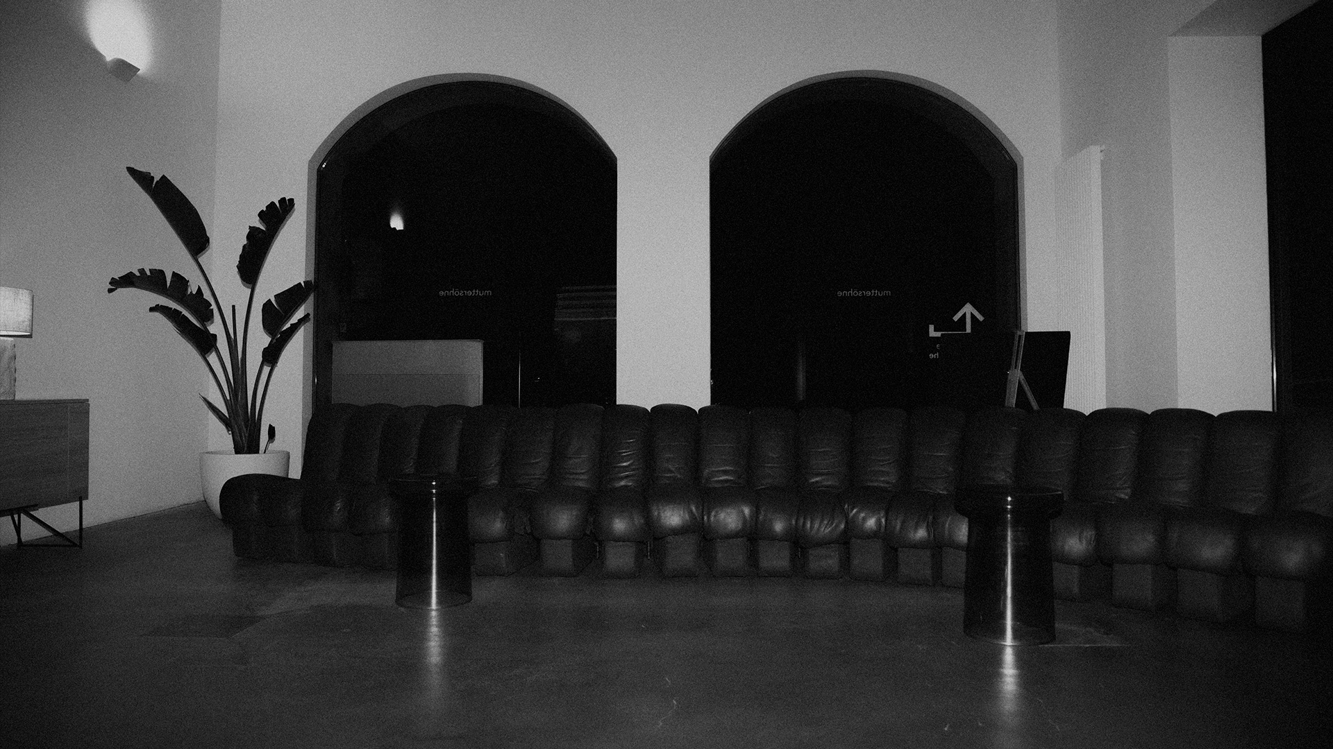 Tattoo-Künstler skizziert ein klassisches Gesichtsbild auf dem Unterarm einer Person, mit einer digitalen Referenz auf einem Tablet nebenan.