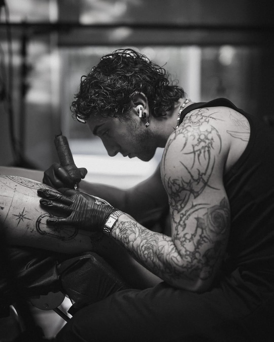 Realistisches Tattoo eines Mannes mit Brille und Bandana, der nachdenklich an seinem Kinn fasst.