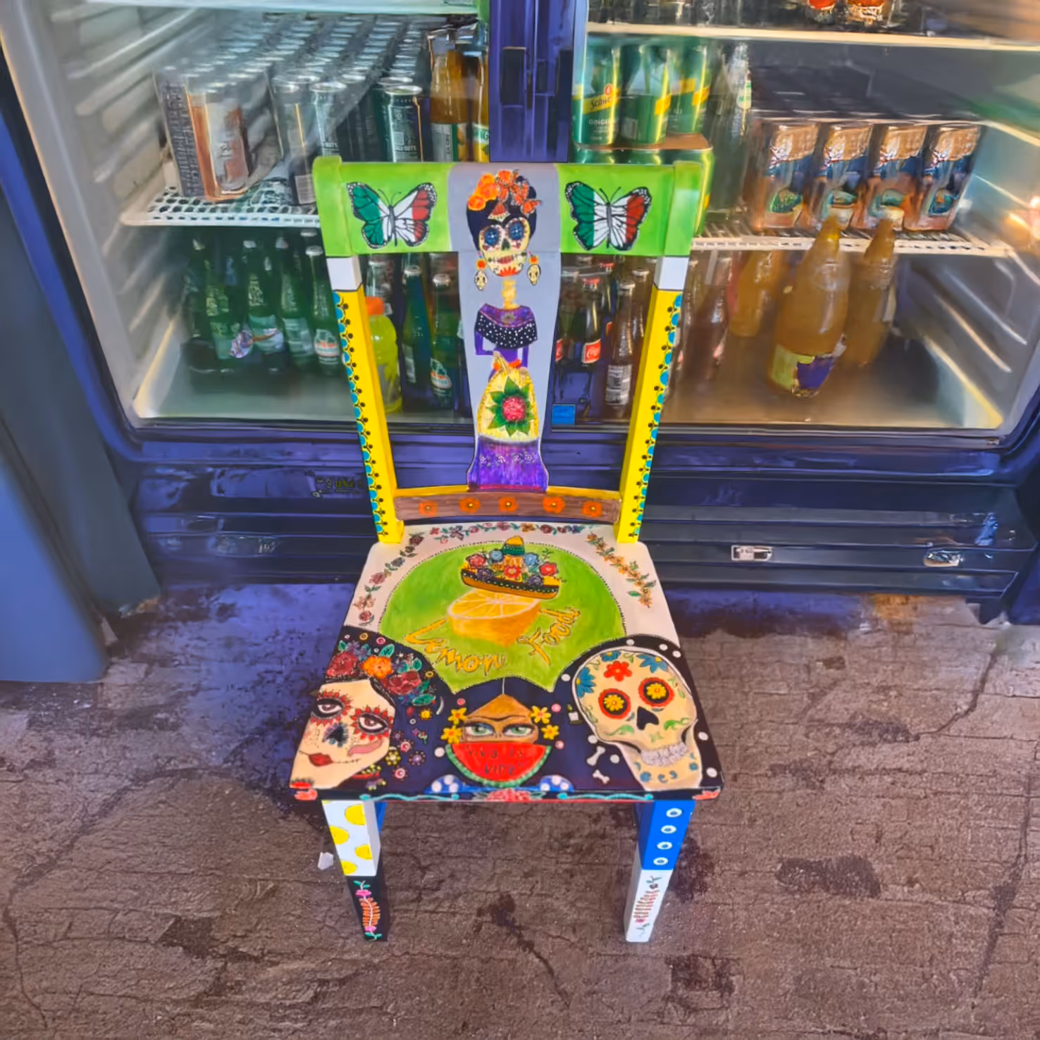 A colorful wooden chair with Dia de Muertos motifs, including skulls and butterflies.