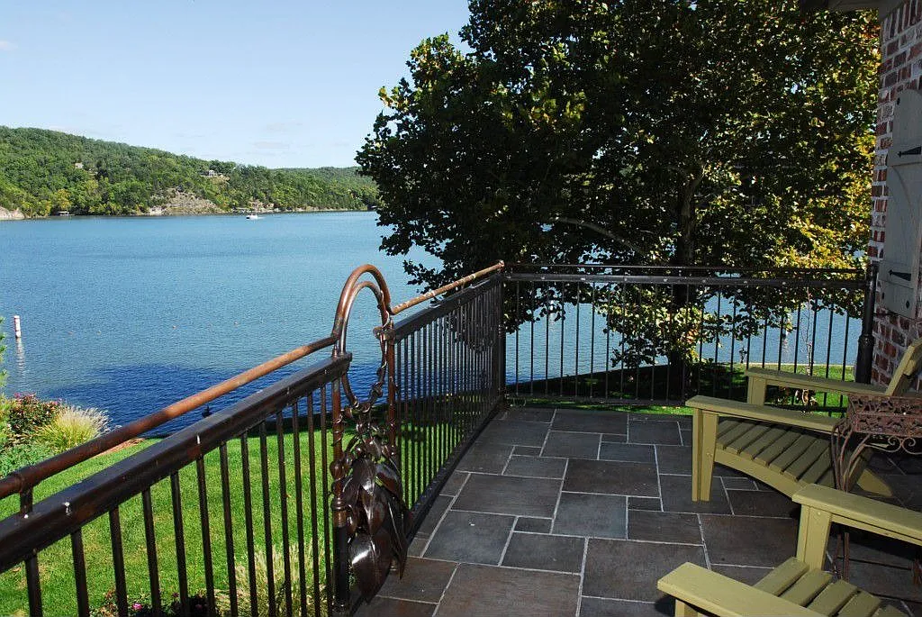 A scenic balcony view overlooking a tranquil lake, surrounded by greenery and blue skies. Perfect for relaxation.