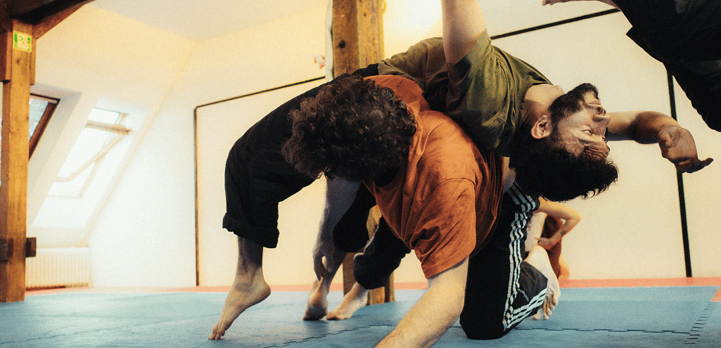 Mitglieder:innen üben eine dynamische Floorwork-Sequenz im Contemporary Dance Training und erforschen Bewegung und Gleichgewicht.