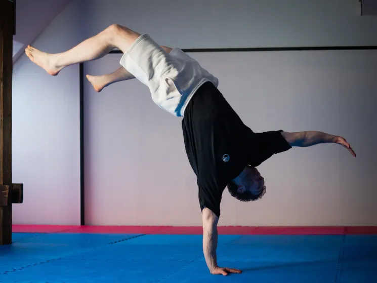 Trainer balanciert auf einer Hand in einer umgekehrten Position.