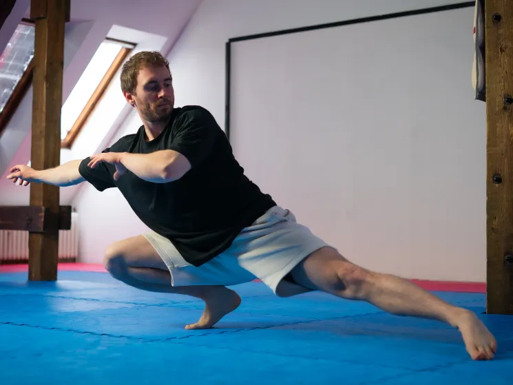 Trainer demonstriert eine tiefe Bewegungsposition auf blauer Matte