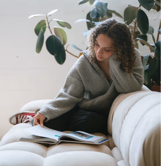 a woman sitting on a couch reading a book