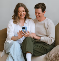 a man and woman sitting on a couch looking at a phone