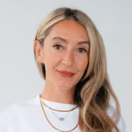 a woman with long blonde hair wearing a white shirt and necklaces