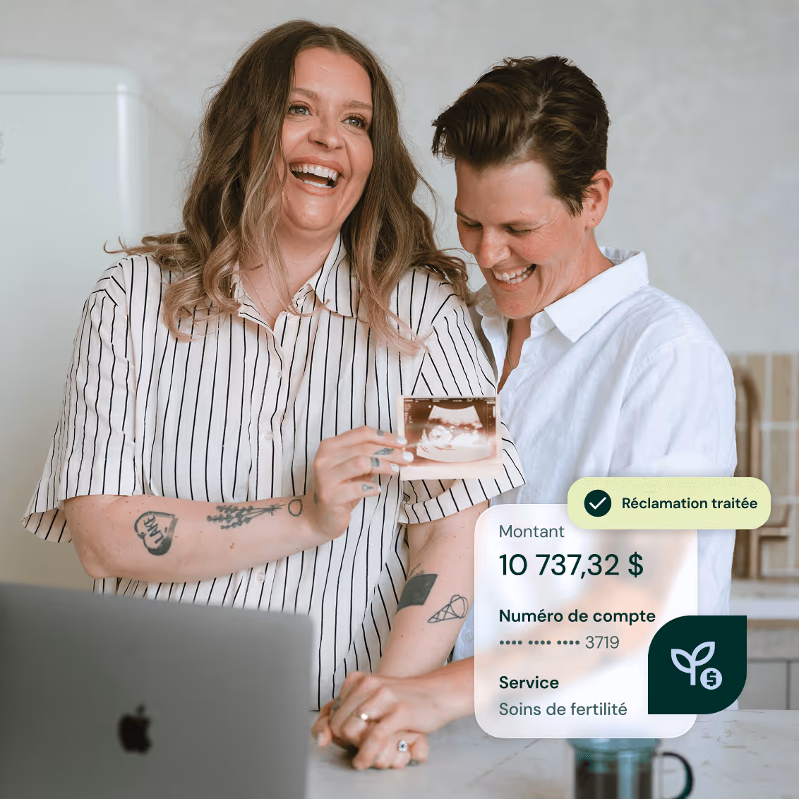 Two happy people holding a fertility ultrasound photo and holding hands near a laptop.
