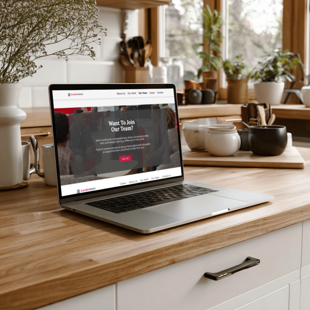 Laptop displaying Causeworx careers page on a wooden kitchen counter with natural light and ceramic dishes