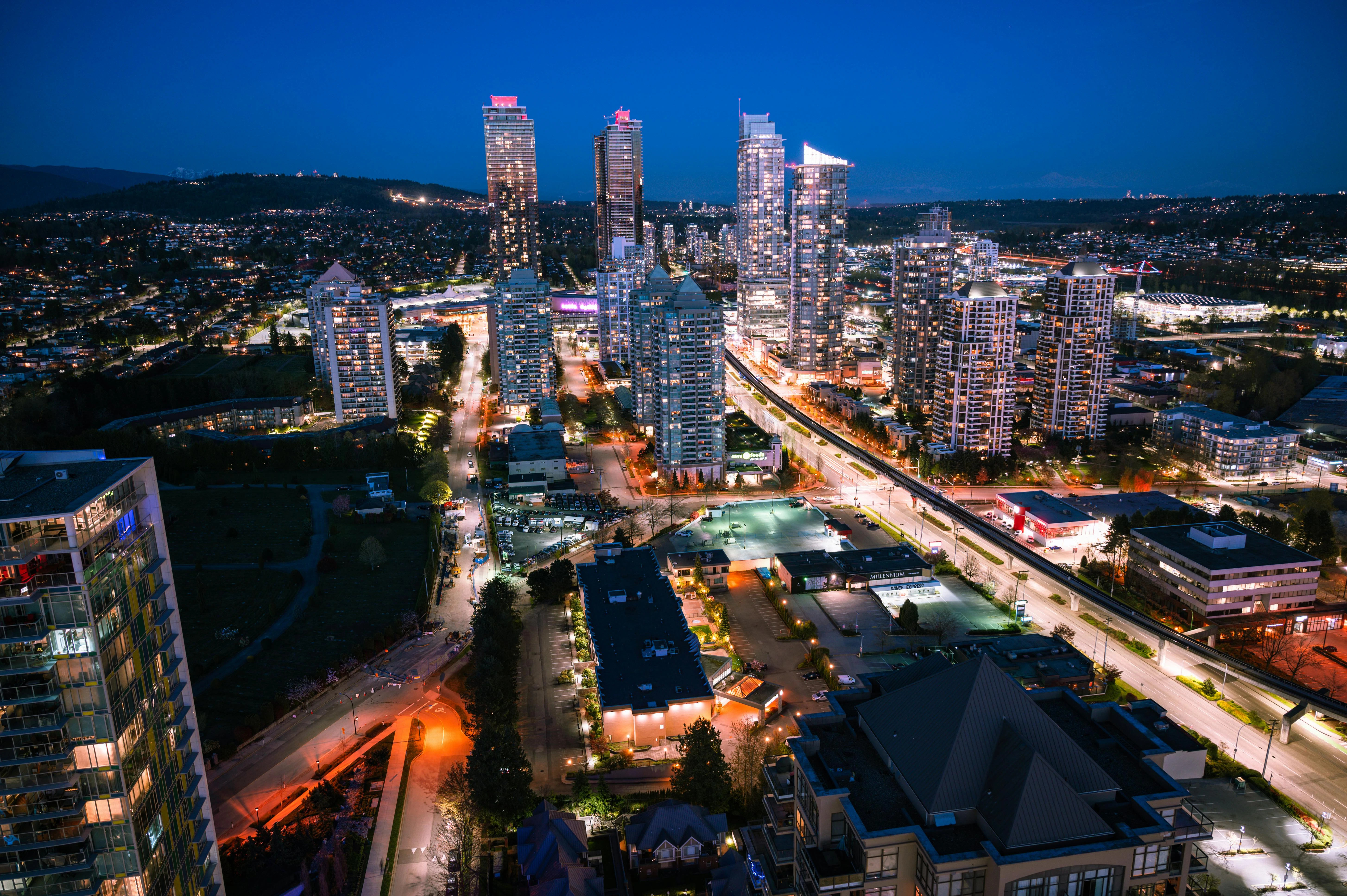 Aerial night view of the illuminated Metrotown skyline and high-rise apartment buildings in Burnaby, British Columbia.