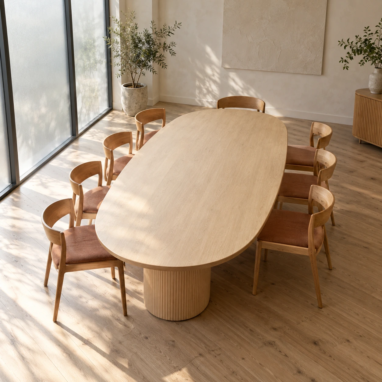 Matching oak chairs with terracotta seats surround an empty oval meeting table in a bright room with frosted windows.