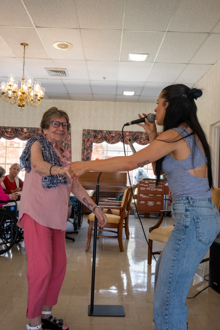 Vocalist connecting with a smiling Senior Living resident during a live Express Entertainment program